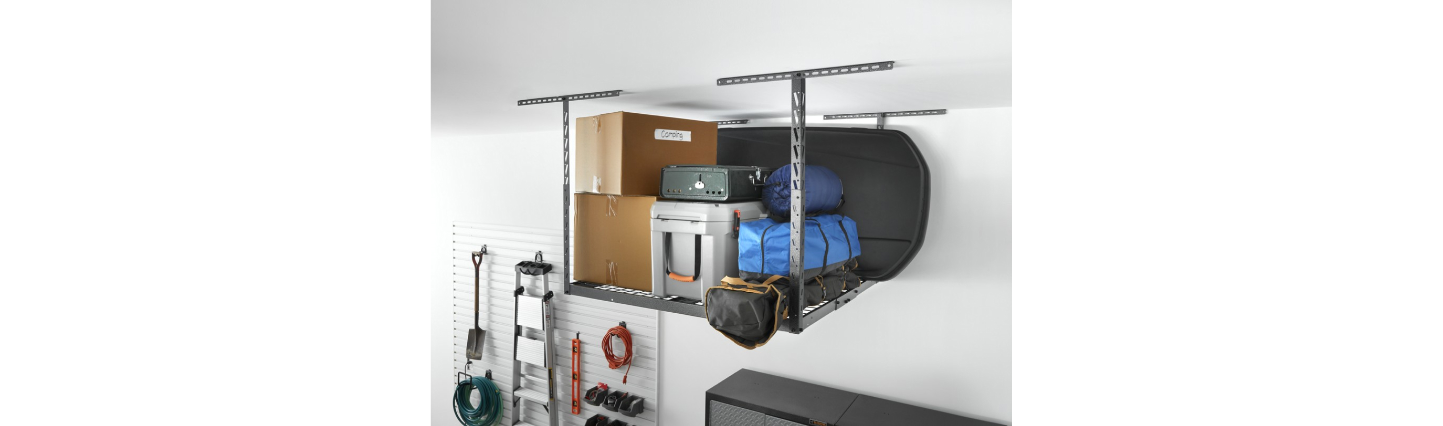 A Gladiator Overhead Storage with various items: two boxes, bins, a case, three bags with camping equipment like a sleeping bag and a black board