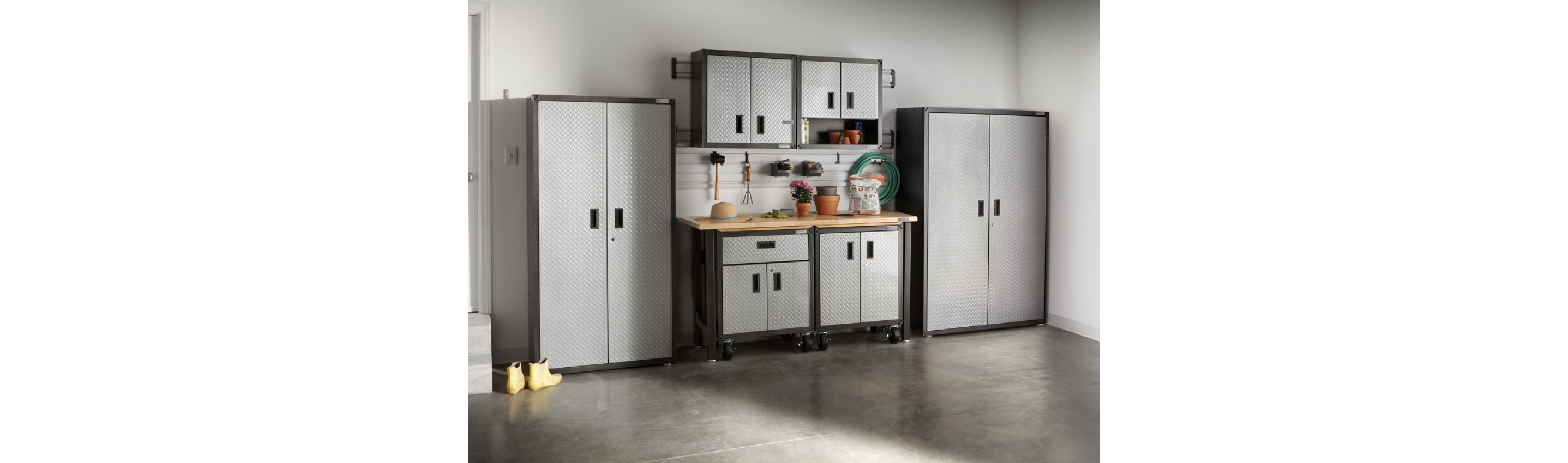 A garage with Gladiator Storage Units and Cabinets. On the workbench are potted plants and other items.