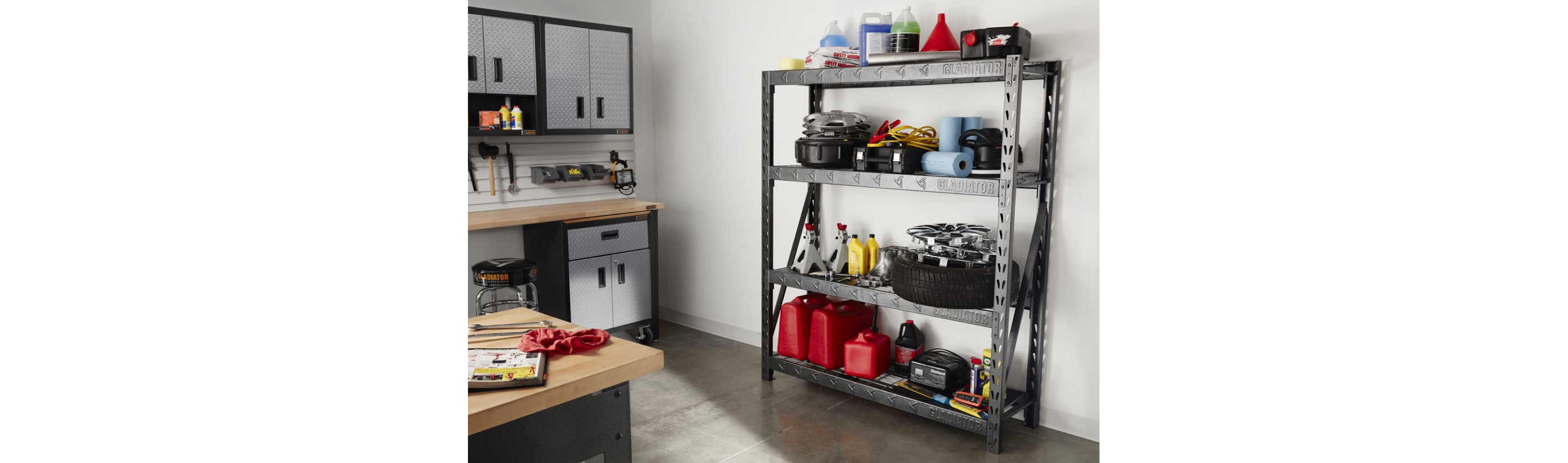  A garage with a Gladiator Shelving Unit. On the shelves are paper towel rolls, jerry cans, tires, rims, car fluids, jumper cables and more. There's also Gladiator Modular Cabinets, a stool and the corner of a workbench. Tools and bins hang on the wall.