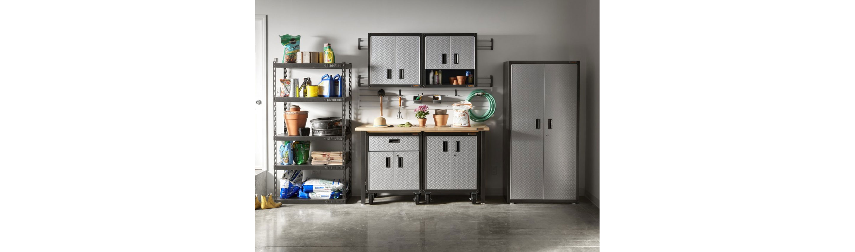 A garage with Gladiator Modular Cabinets, a Gladiator Workbench and a Gladiator Rack Shelving. The rack shelving is filled with gardening items like plant pots, bags of soil, yard waste bags and more. On the modular cabinets are a sun hat, potted plants, a bag of soil and more. Hanging on the wall are gardening tools and a garden hose